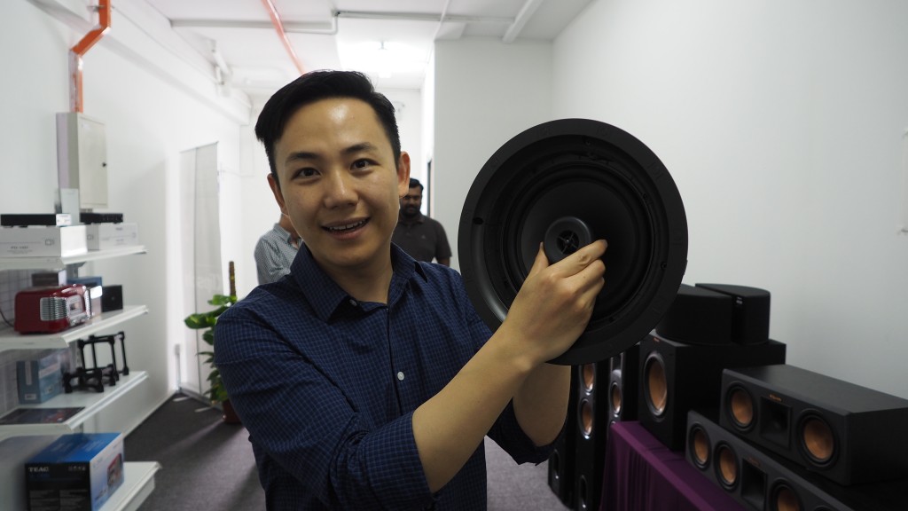 Chuck Chen showing the Klipsch ceiling speaker for Atmos which has a tweeter that can be moved to face the listener.