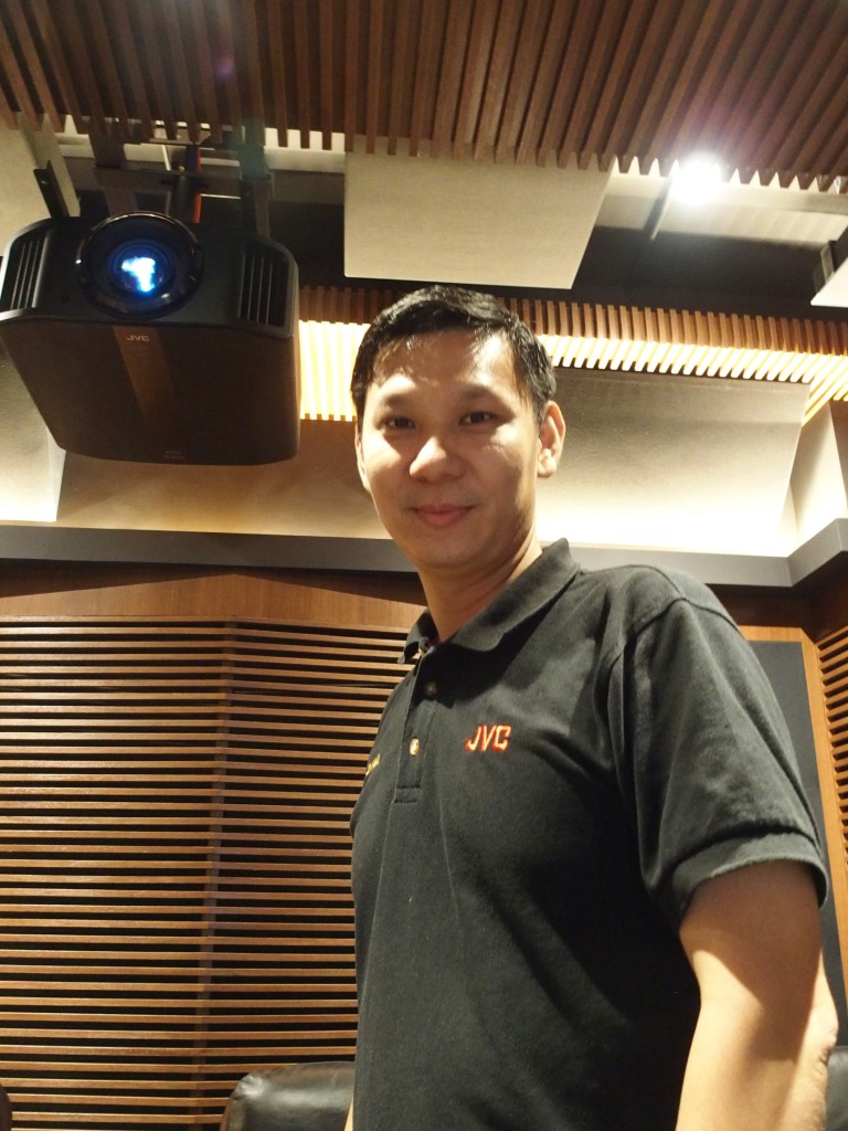 Steven Woo of Klingen & Erlesen and thr 8K e-shift JVC DLA-NX9 projector above him.