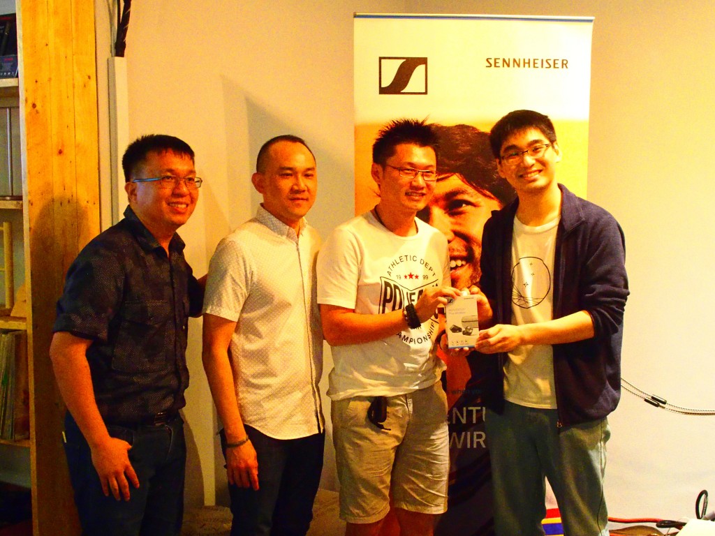Senior product manager of Sennheiser Electronic Asia Pte Ltd Kuan Wee Hong (left), sales manager Charles Chan (second from left) and  director of Stars Picker Lim Hai Wei (right) presenting a pair of headpones to a winner of the lucky draw.