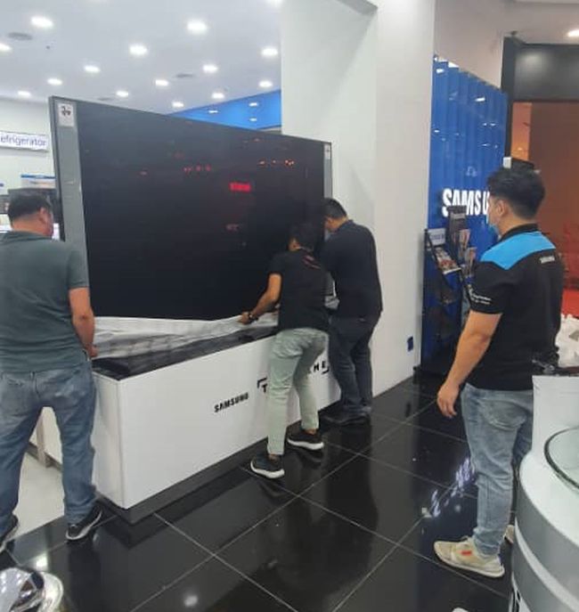 It takes a few strong men to set up the huge TV.